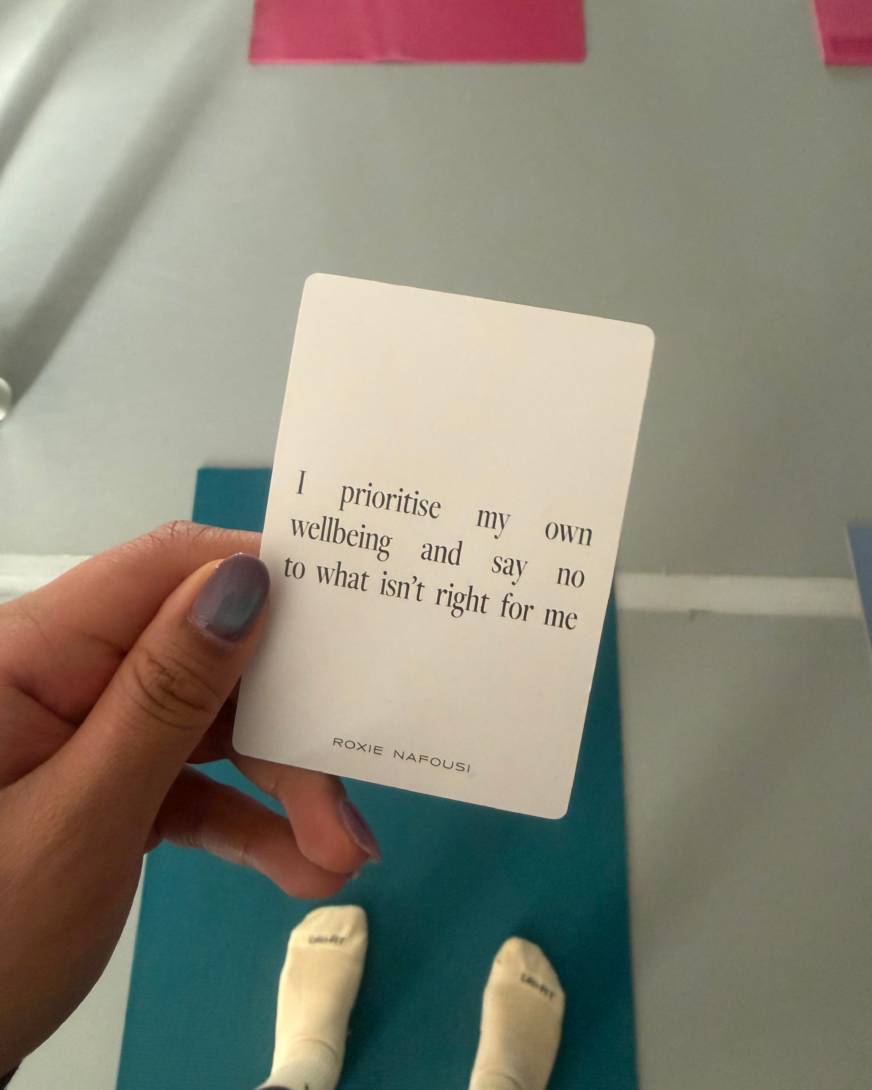 Close up of a hand with a card saying ' I prioritise my own wellbeing and say no to what isn't right for me'.