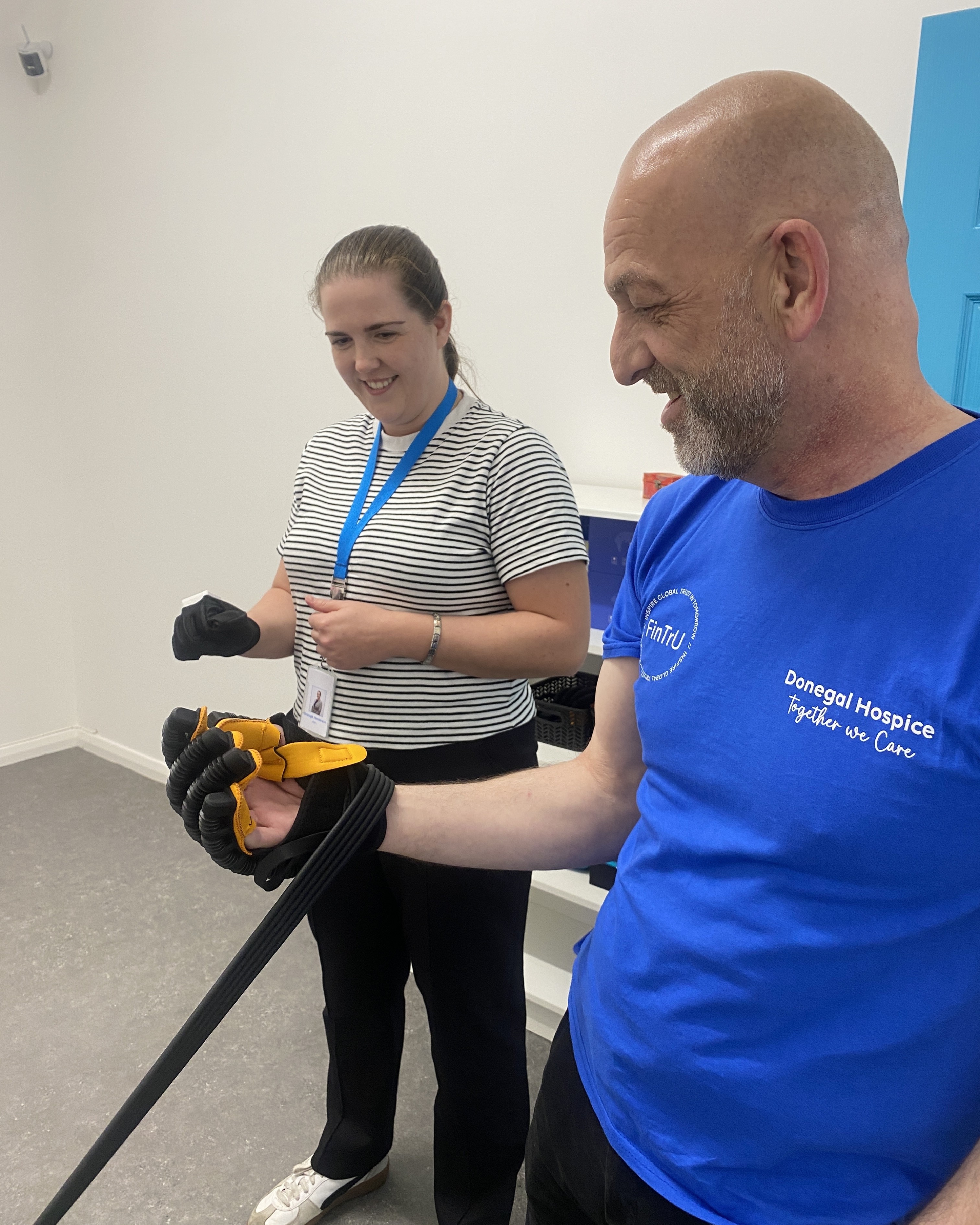 A man with his hand in a glove attached to elastic with a woman watching on