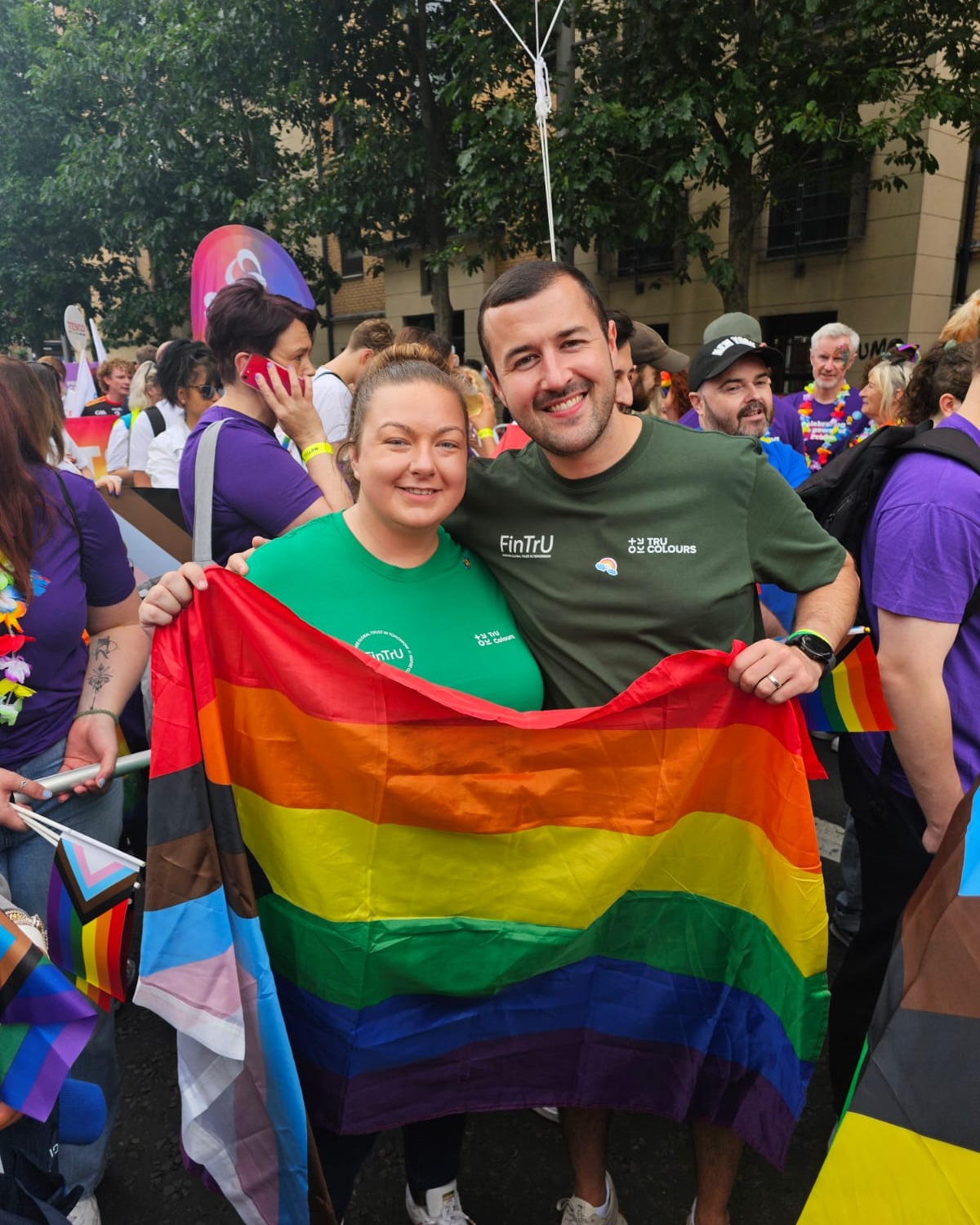 Two people holding a rainbow flag